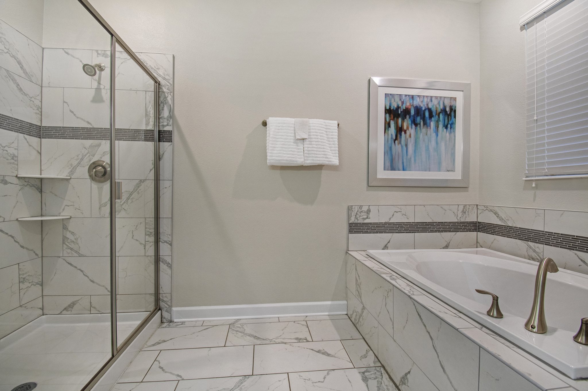En-suite bathroom with a glass shower, soaking tub, and marble tile