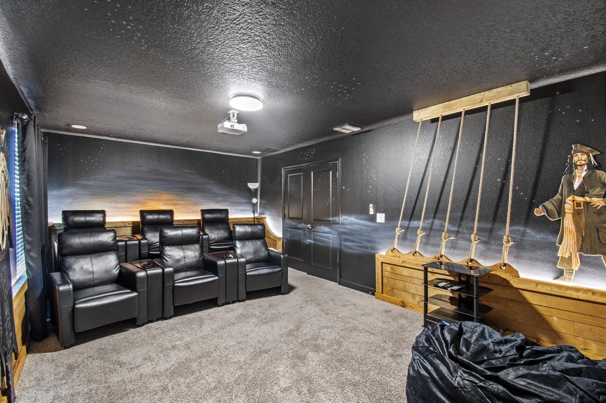 Pirates-themed theater with reclining seats, a ceiling projector, and ship-riggi