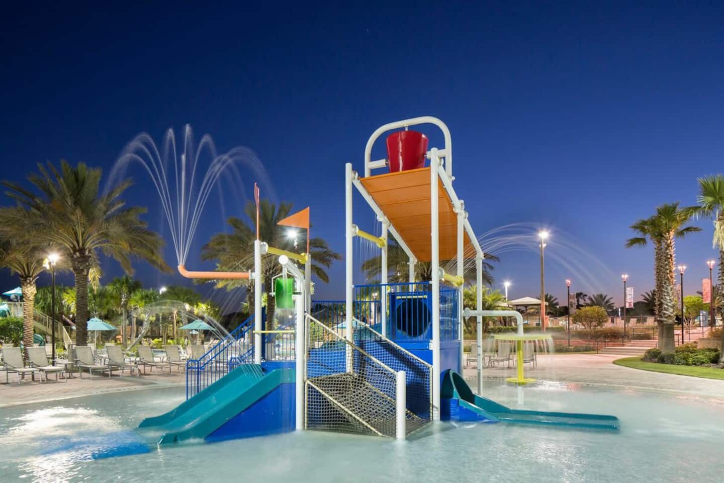 Resort access: splash pad with slides, fountains, and palm-lined seating