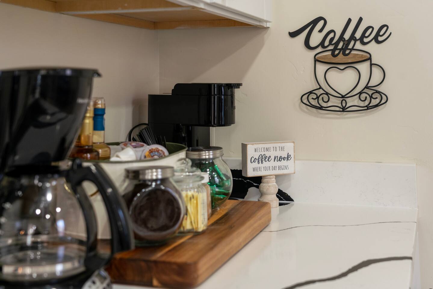 Coffee nook stocked with a drip coffee maker, Keurig, and assorted flavorings an