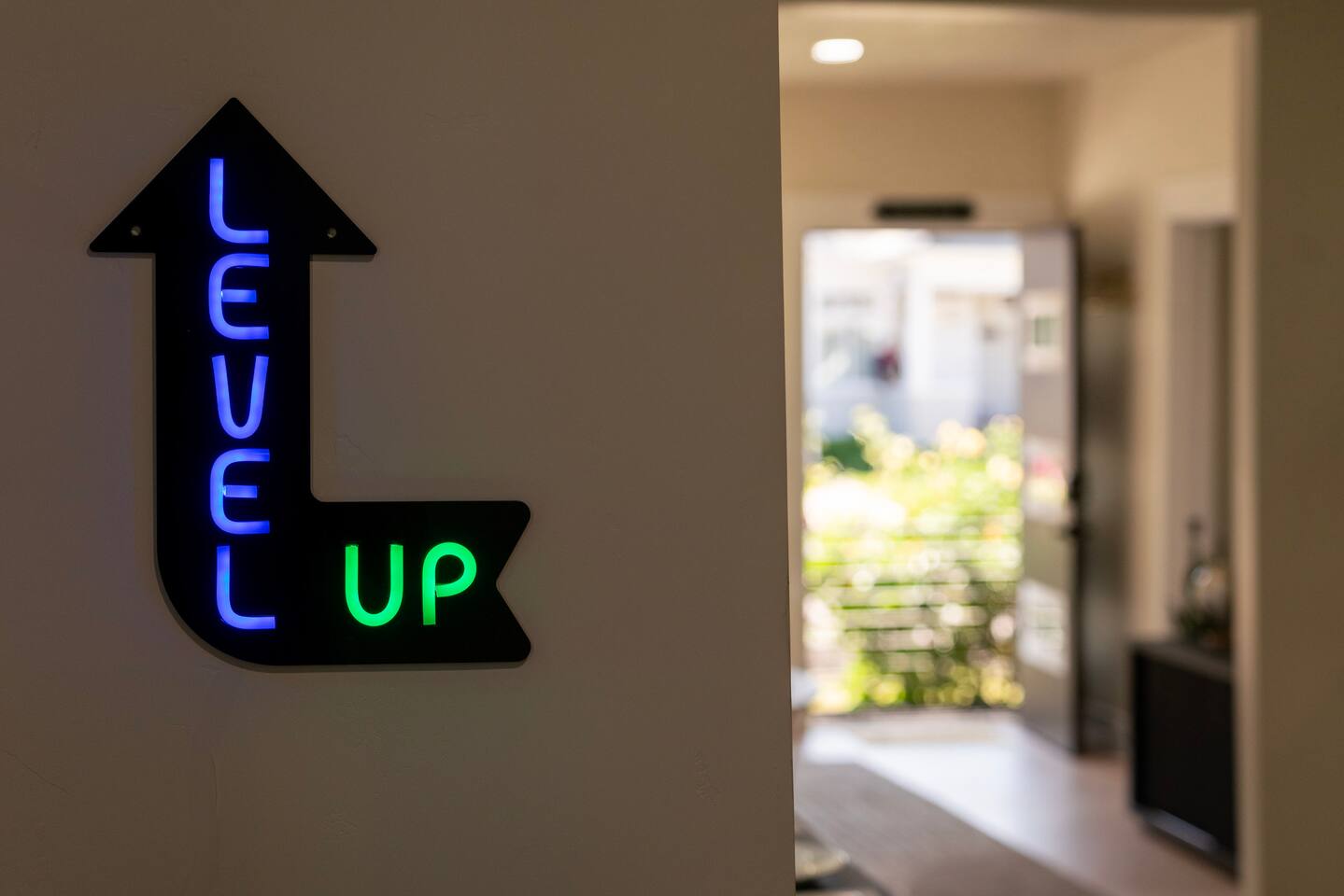 Glowing Level Up neon sign marks the home's arcade corner.