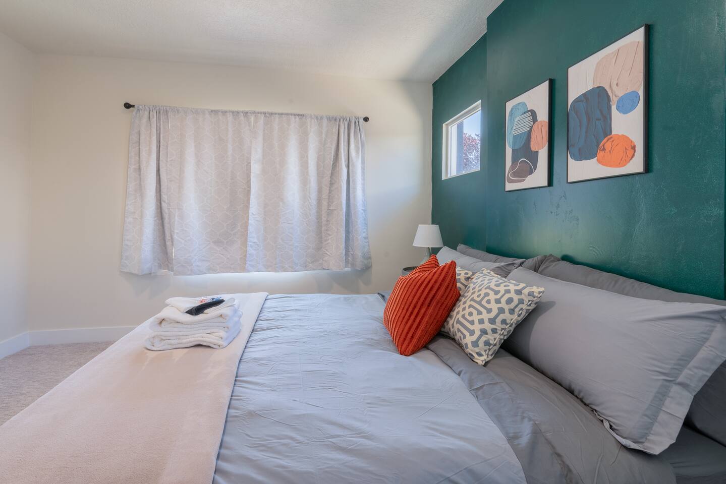 King bedroom from another angle with layered bedding, a nightstand lamp, and bri