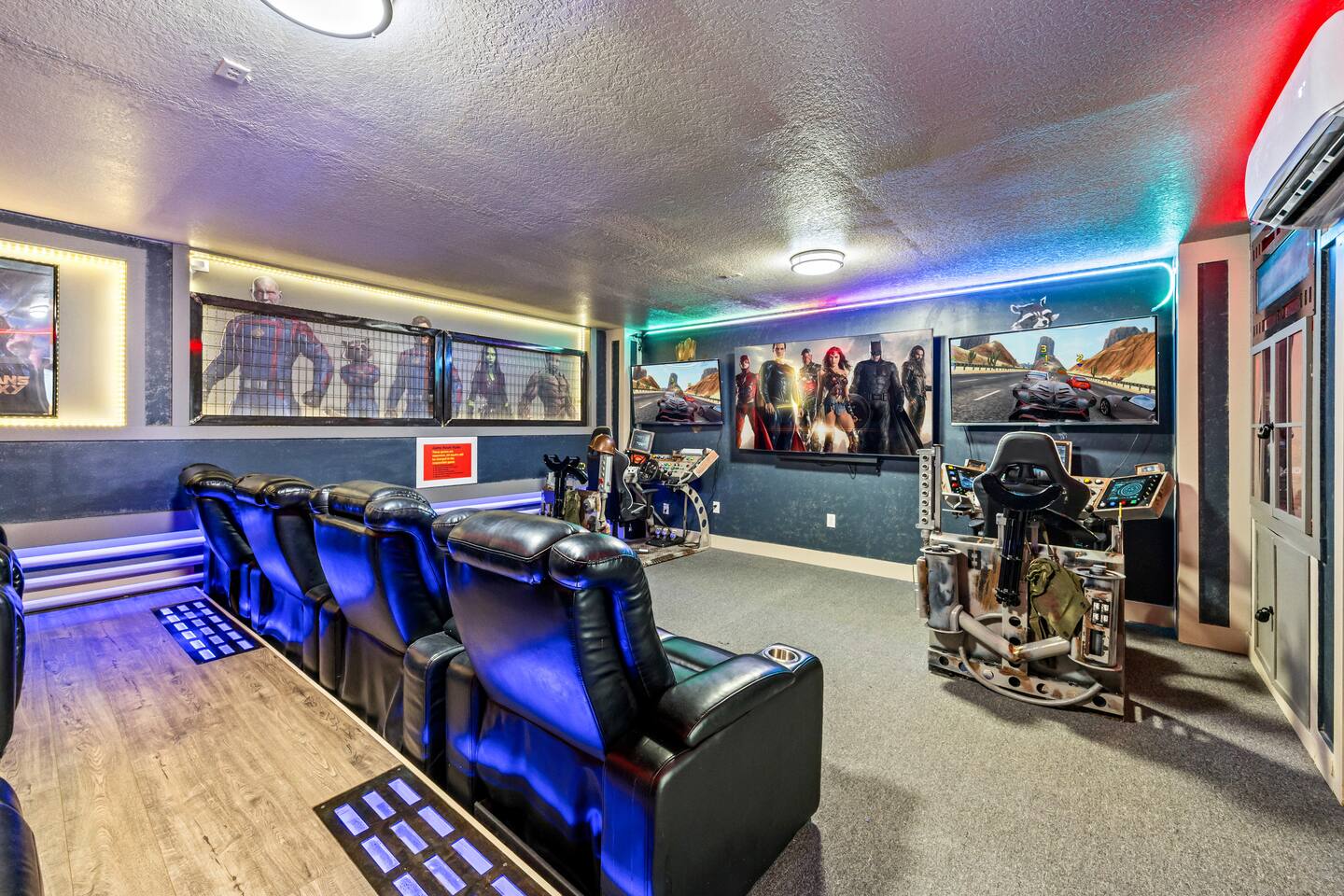 Game room and theater with blue-lit recliners, racing simulators, and superhero 