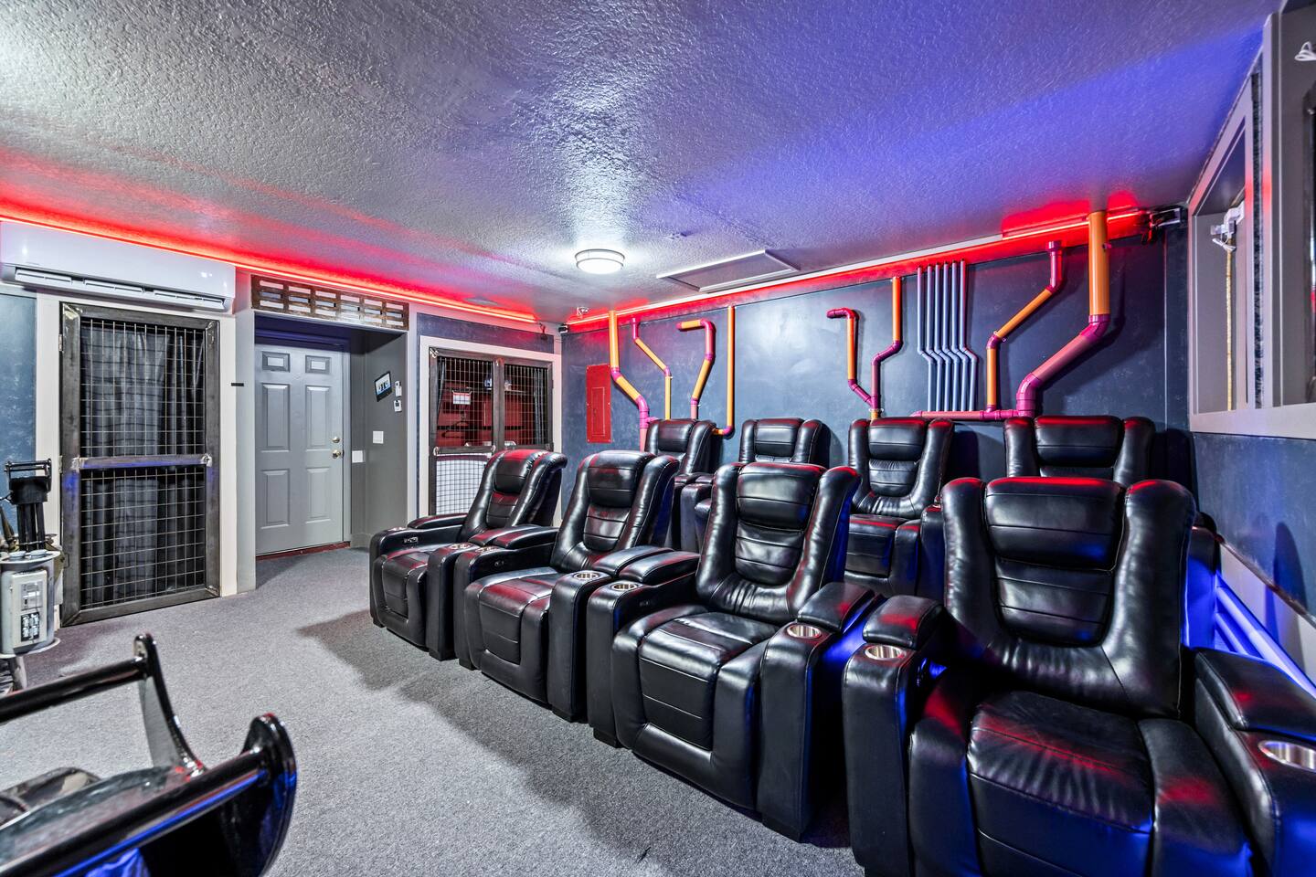 Home theater with tiered black leather recliners, industrial pipe wall decor, an