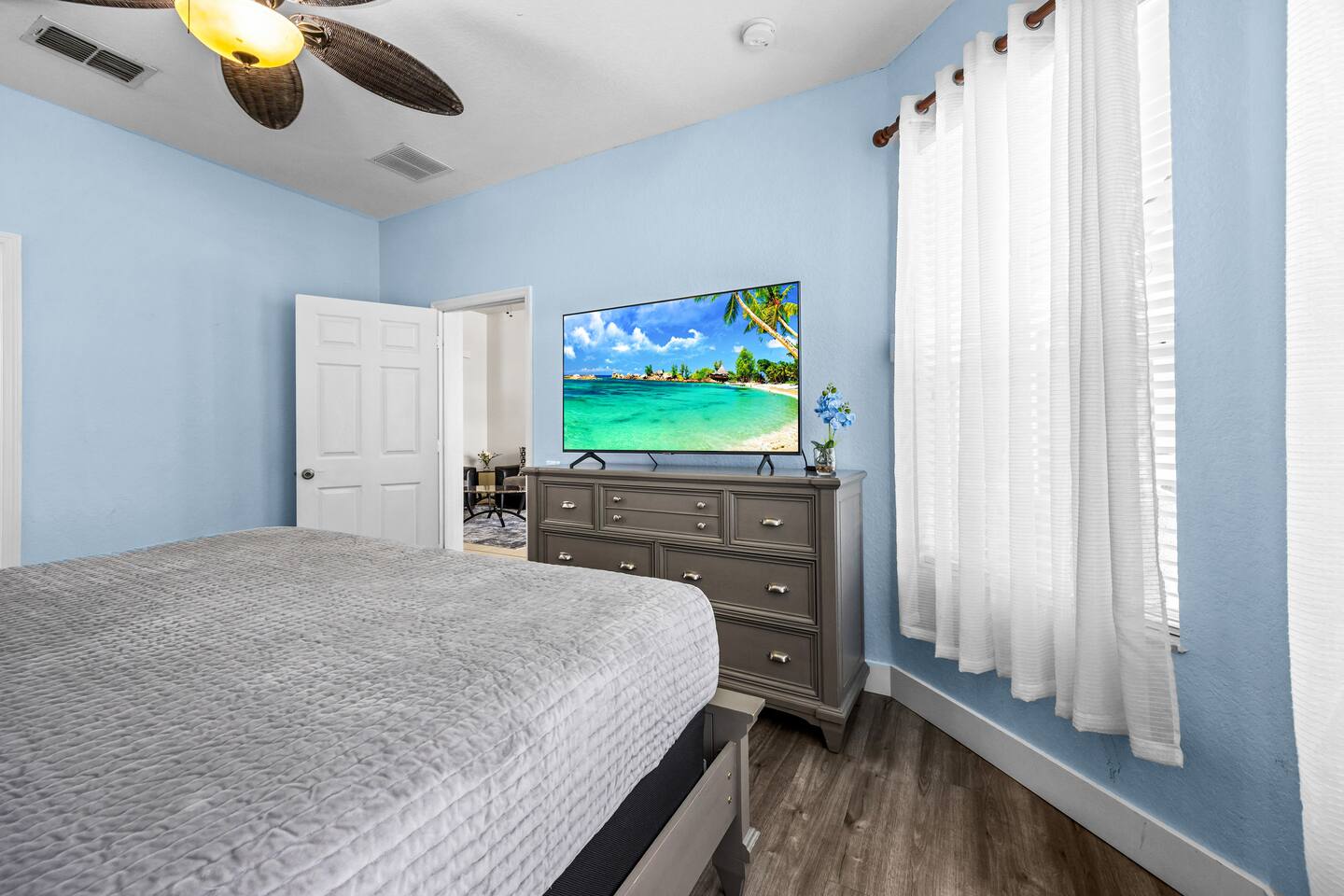 King bedroom with a wooden sleigh bed, a dresser with TV, and bright blue walls.