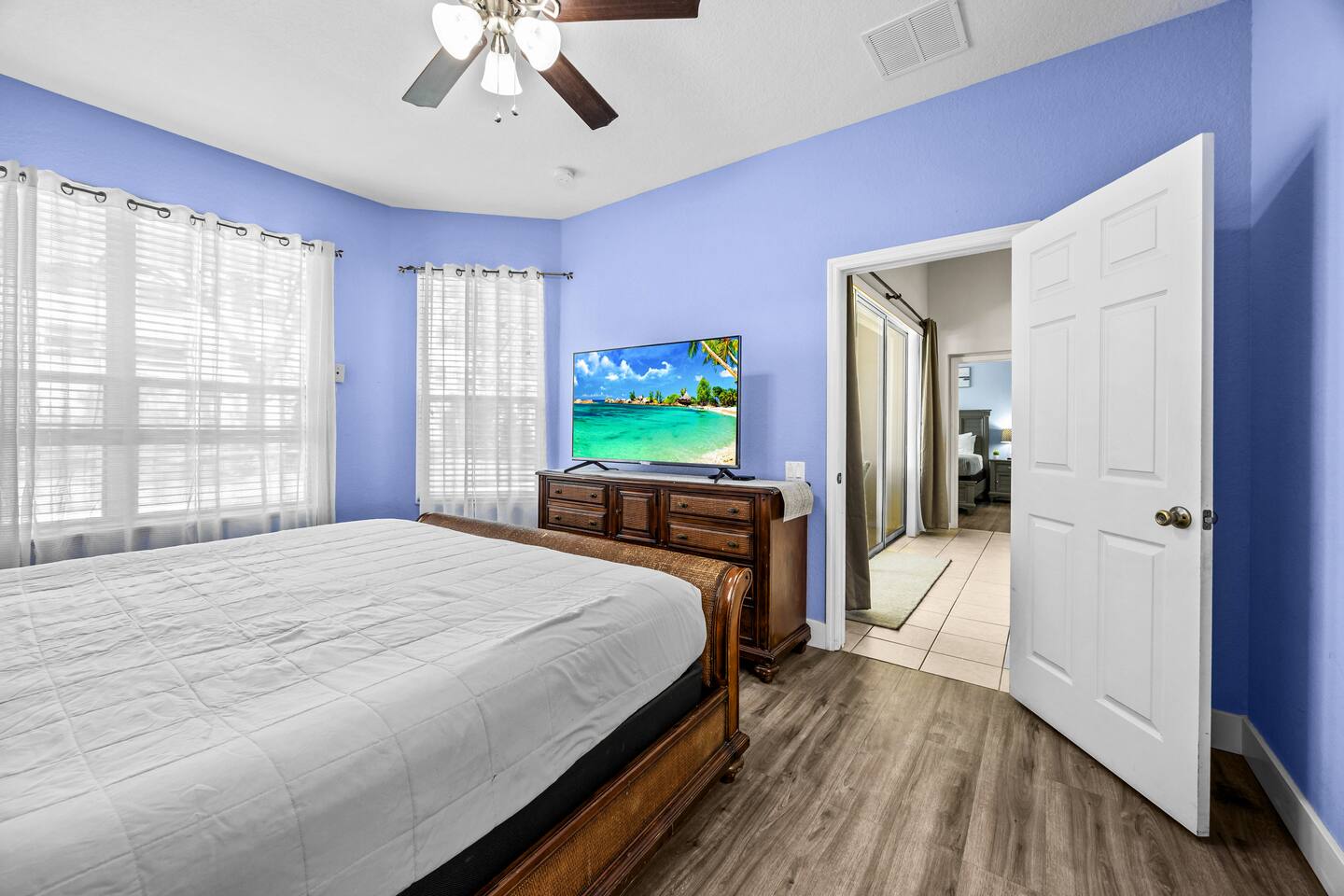 King bedroom with a wooden sleigh bed and dresser, doorway open to the hall.