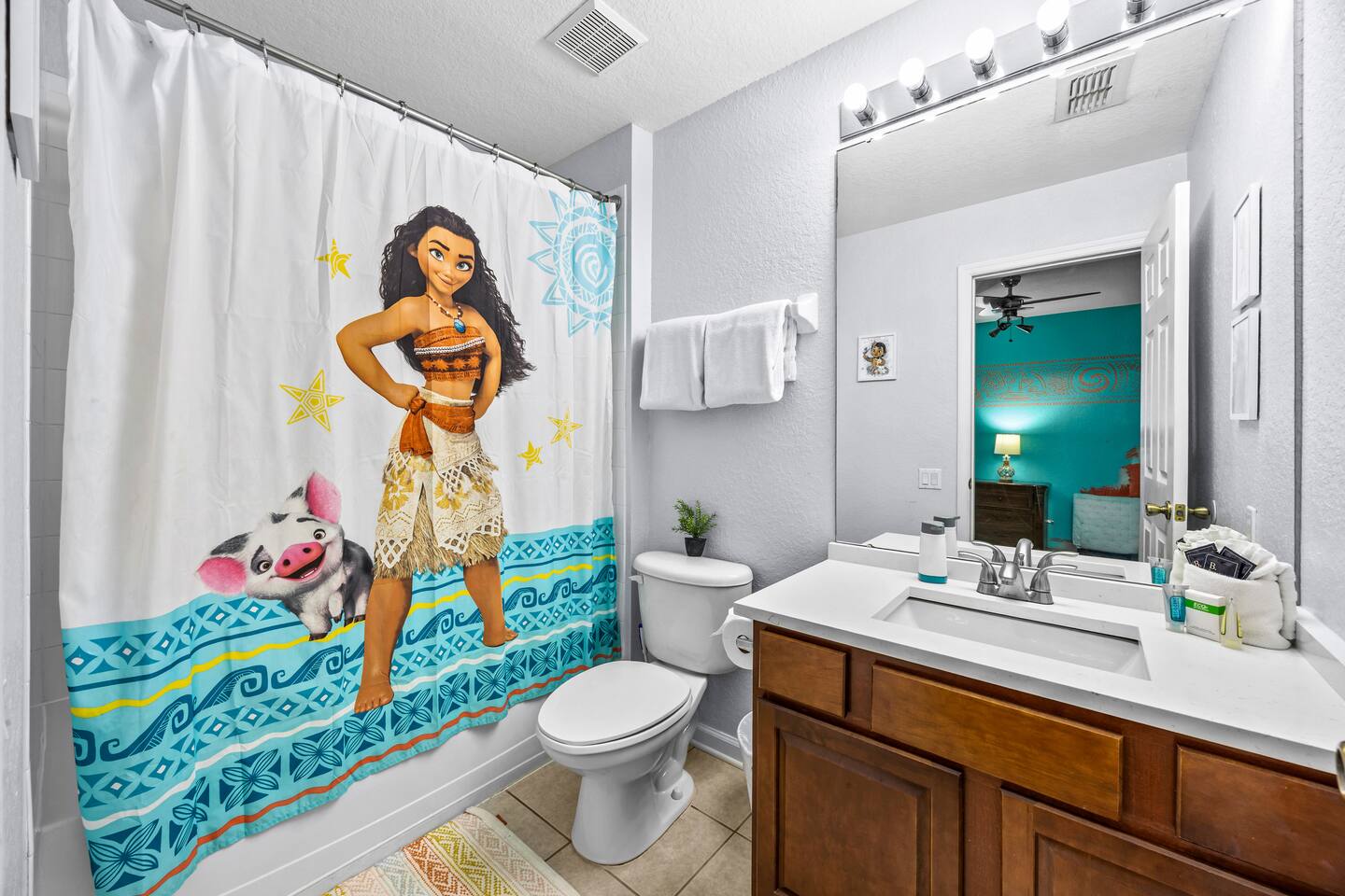 En-suite bathroom with a Moana shower curtain, tub/shower combo, and single wood