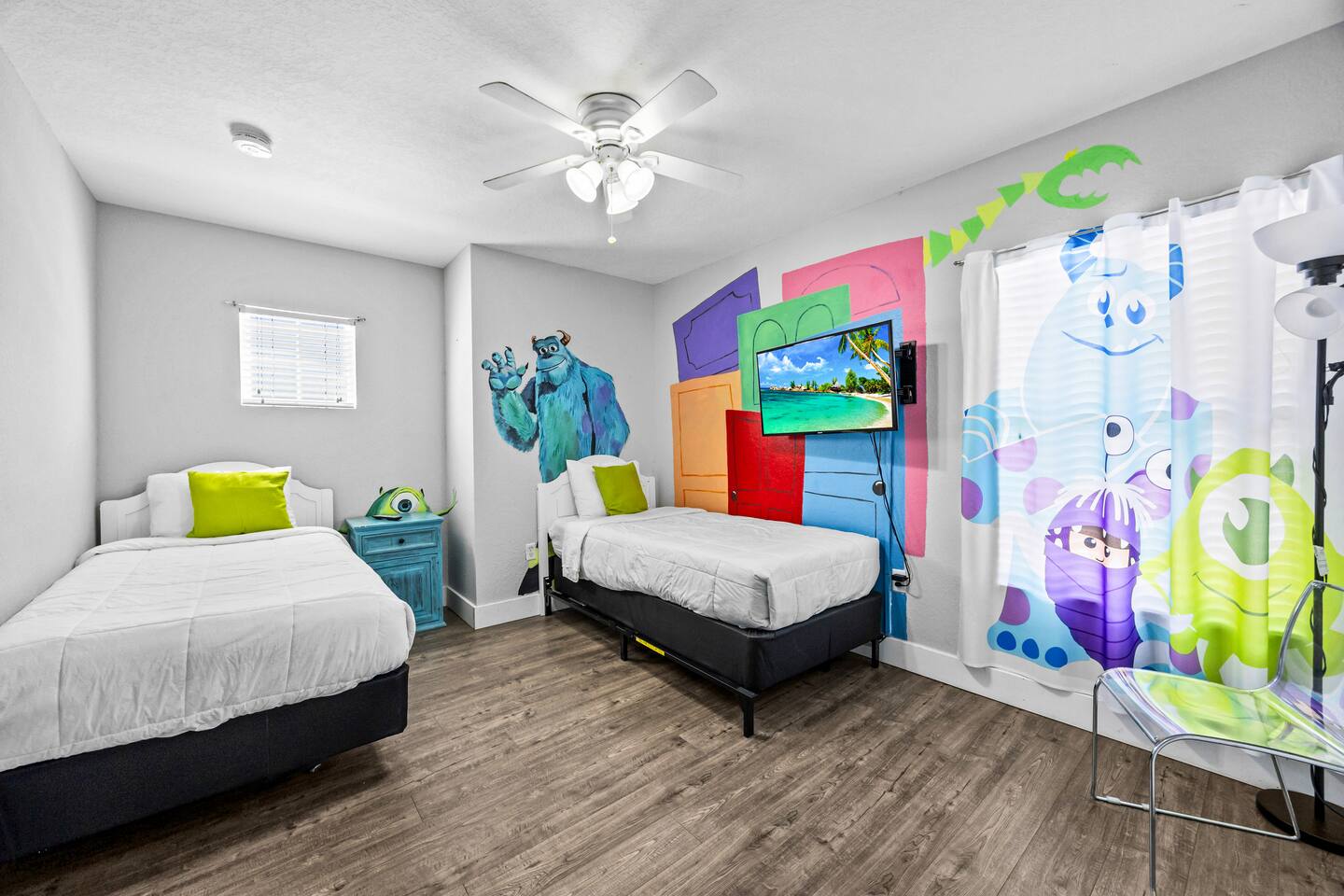 Monsters Inc-themed bedroom with two twin beds, a Sully mural, and colorful deco