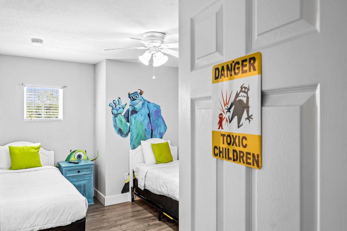 Monsters Inc-themed twin bedroom with a character mural and playful door sign.