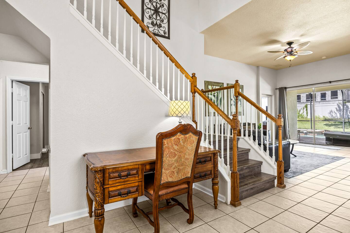 Entry foyer with a writing desk and staircase, tile flooring, and pool views bey