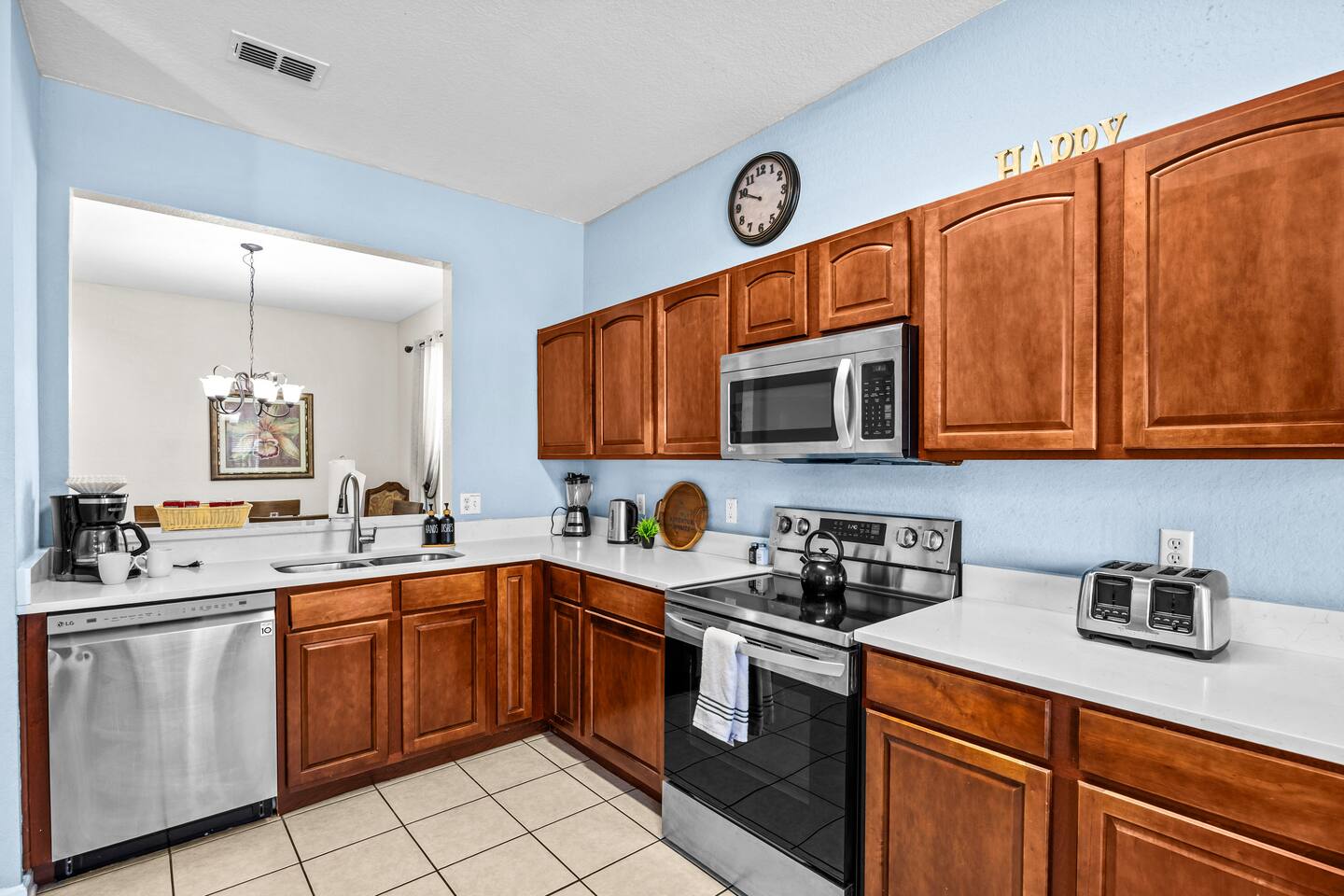 Kitchen and adjoining living space with tile flooring and stainless appliances.