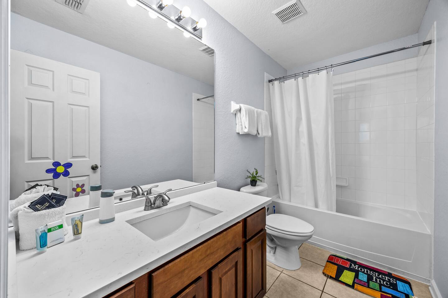 Bathroom with a tub/shower combo, single vanity, and a themed bath mat.
