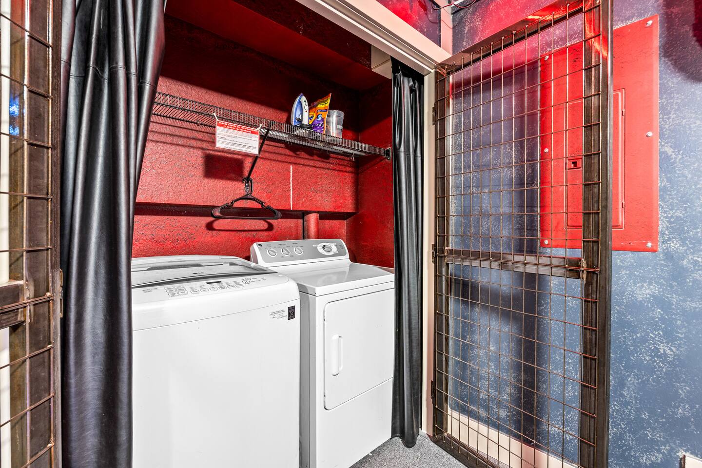 Laundry closet with a full-size washer and dryer, shelving, iron, and hanger.