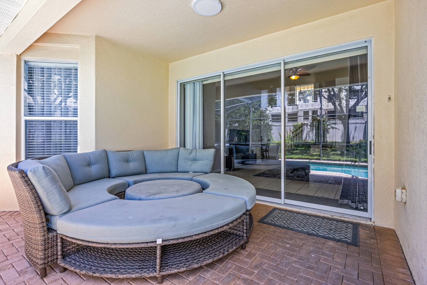 Covered lanai with a round wicker daybed and sliding-glass doors to the interior
